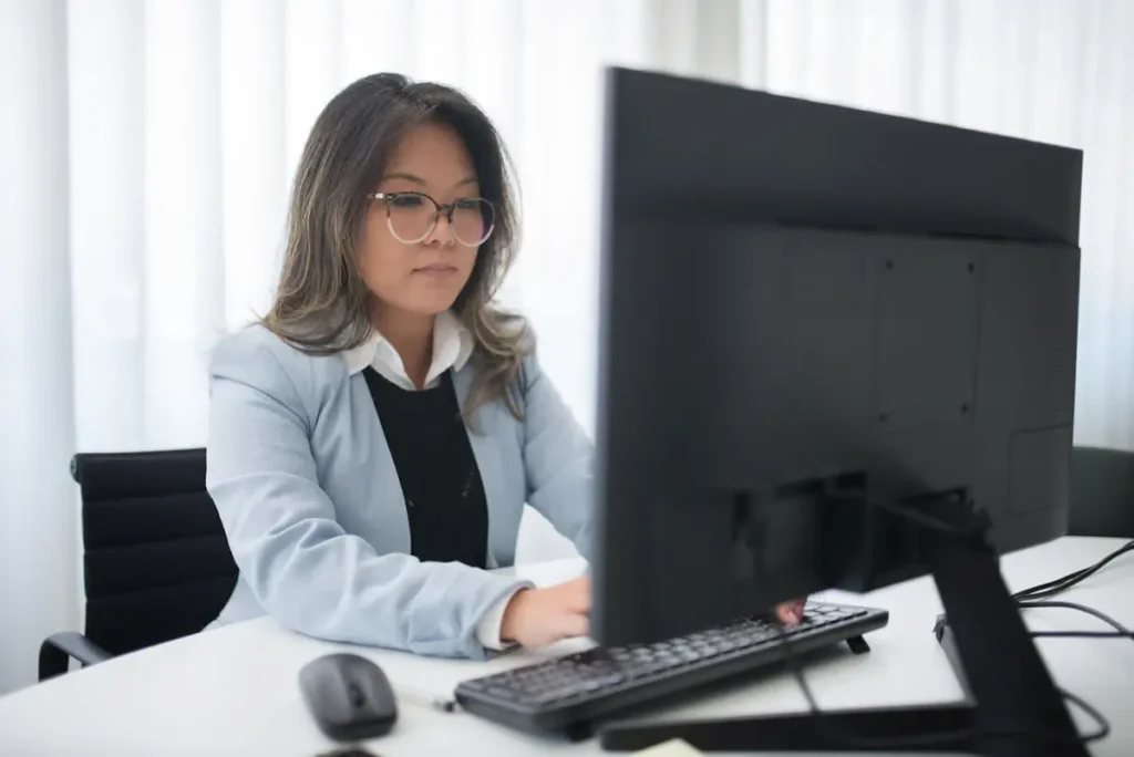 Woman in blazer typing on laptop using Winslow HR assistant